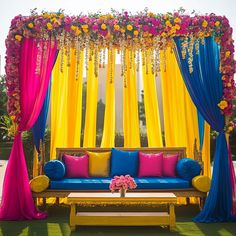 a blue couch sitting under a yellow and pink drape with flowers on the back