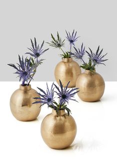 three gold vases with purple flowers in them