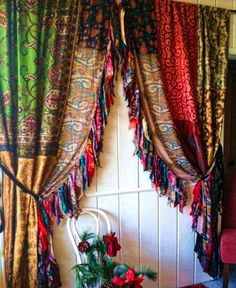 a chair sitting in front of a window covered in colorful drapes and tassels