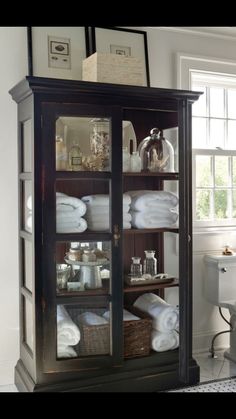 an old china cabinet with linens in it