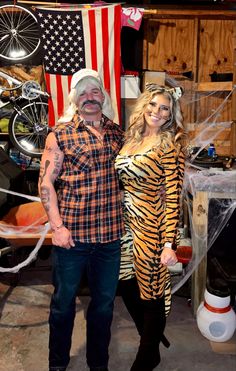 the man and woman are dressed up as tiger costumes for halloween, posing in front of an american flag