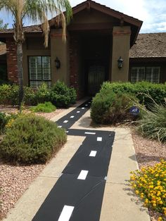 a house that has been painted black with white stripes on the walkway and yellow flowers in front