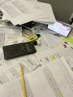 a calculator sitting on top of a pile of papers next to a keyboard