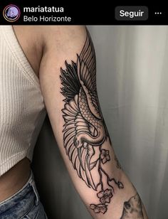 a woman's arm with a bird and flowers tattoo on the left side of her arm