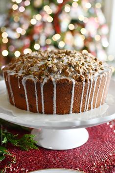 a cake sitting on top of a white plate next to a christmas tree with lights in the background