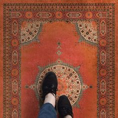 a person standing on top of an orange rug