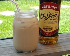 homemade iced coffee in a jar with a straw and bottle next to it on a picnic table