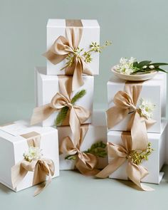 four white boxes with bows and flowers on them are stacked up in front of each other