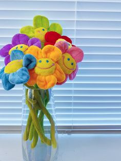 a vase filled with lots of colorful stuffed animals sitting on top of a window sill