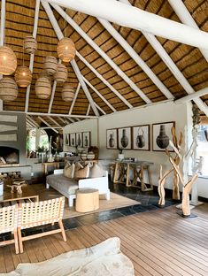 a living room filled with lots of furniture under a wooden ceiling covered in wicker lamps