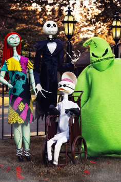 three people dressed in halloween costumes standing next to each other near a pumpkin and monster statue