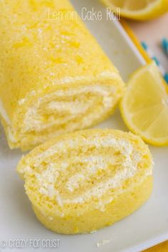 lemon cake roll on a white plate next to sliced lemons