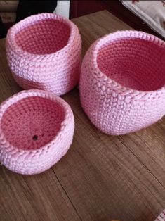 three pink knitted baskets sitting on top of a wooden table