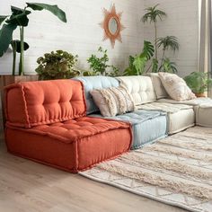 an orange and blue couch sitting on top of a wooden floor next to a white rug