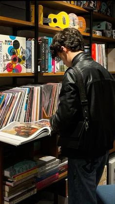 a man standing in front of a bookshelf filled with vinyl records and cds