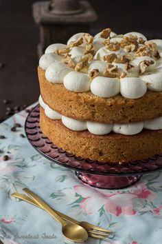 a cake with white frosting and marshmallows on top sitting on a plate