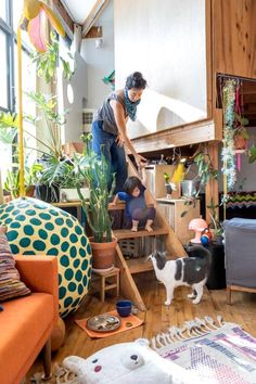 a woman and her child are playing on the stairs in their living room with plants