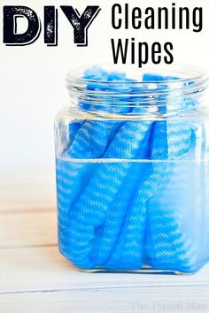 a jar filled with blue cleaning wipes on top of a wooden table