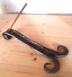 an old iron hook with a wooden stick sticking out of it's end on top of a wood table