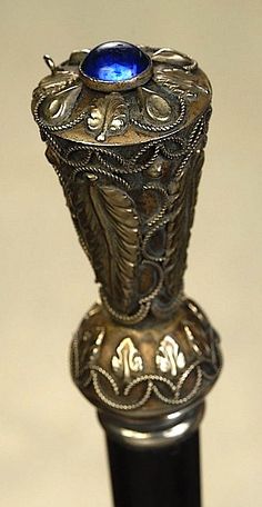 an ornate silver vase with a blue stone in it