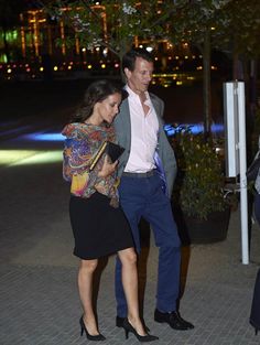 a man and woman are walking down the street at night with their cell phones in hand