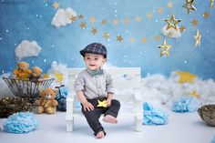 a little boy sitting on a white bench in front of blue and gold stars backdrop