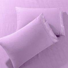 two pillows on a bed with purple sheets