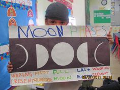 a young boy holding up a sign that says moon phases