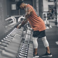 a man in an orange shirt and white shorts is working on some metal bars at a gym