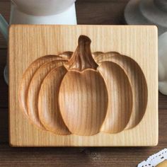 a wooden carving of three pumpkins on top of a cutting board next to a knife