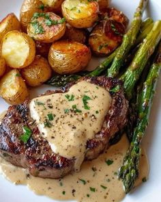 steak, potatoes and asparagus on a white plate with gravy sauce