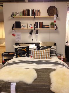 a bed room with a neatly made bed and some books on the shelves above it