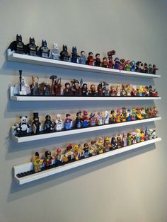 three white shelves filled with lego figurines on top of each other in front of a wall