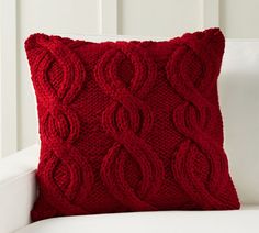 a red knitted pillow sitting on top of a white couch