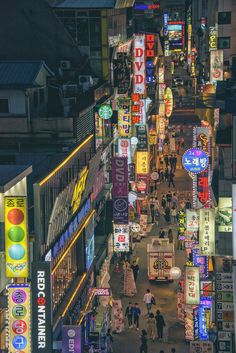 an overhead view of a city street at night with neon signs and people walking on the sidewalk