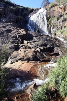 there is a waterfall in the middle of some rocks and plants on the side of it