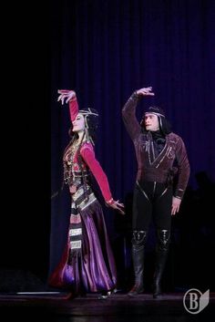 two people in costume standing on stage with one holding his hand up to the other