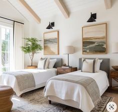 two beds in a bedroom with white walls and wood beams on the ceiling above them