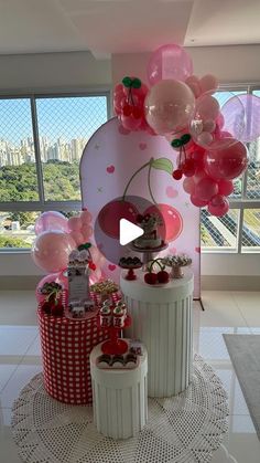 balloons and cakes are on display in a room with large windows, overlooking the city