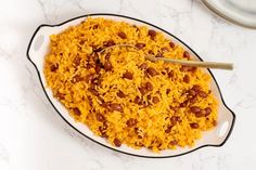 a bowl filled with rice and beans on top of a white counter next to a spoon