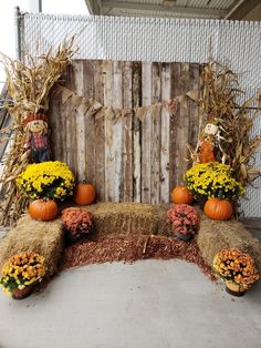 an outdoor fall decoration with hay and pumpkins