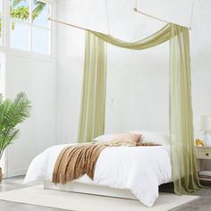 a bedroom with a white bed and orange drapes hanging from the ceiling over it