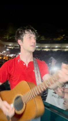 a man playing an acoustic guitar in front of a crowd