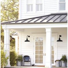 a white house with two black lamps on the porch