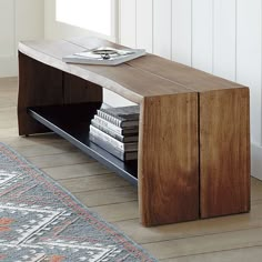 a wooden table with magazines on it in front of a rug and door to another room