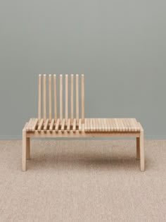 a wooden bench sitting on top of a carpeted floor next to a gray wall