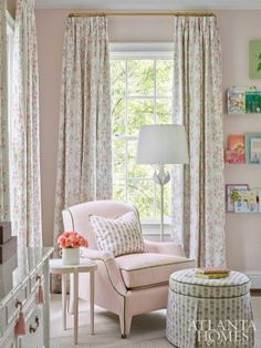 a living room with pink walls and floral drapes on the windowsill, a white chair and ottoman in front of a window