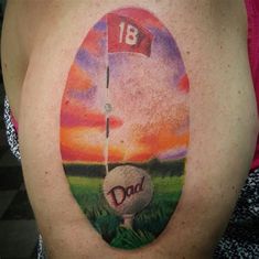 a woman with a golf ball and flag tattoo on her back shoulder, in front of a sunset