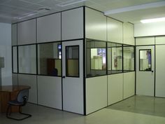 an empty room with glass partitions and a desk in the corner, next to a chair