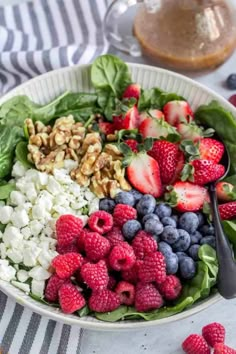 a bowl filled with spinach, strawberries, blueberries and feta cheese